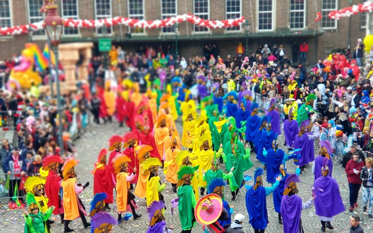 Die KG Regenbogen zieht beim Rosenmontagszug in bunten Kostümen über den Marktplatz.