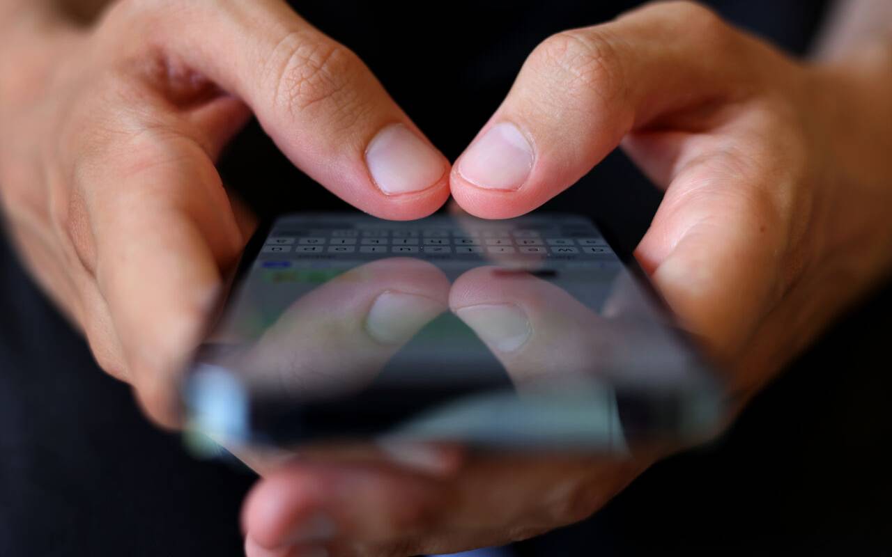 Ein Mann tippt auf einem Smartphone eine WhatsApp-Nachricht.