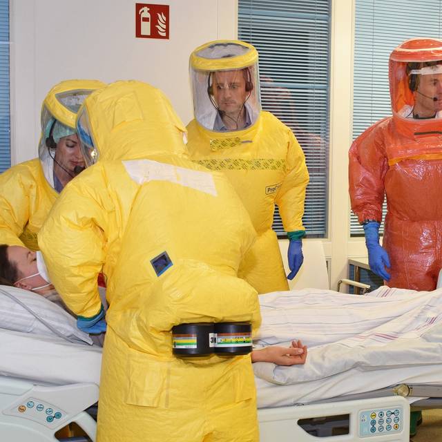 Retter in gelben und orangenen Schutzanzügen versorgen eine Patientin im Rahmen einer Hochinfektions-Übung.