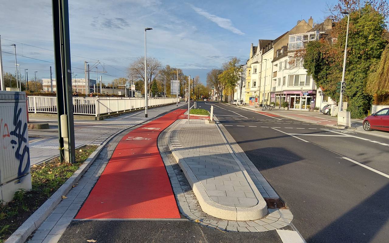 Neuer Radweg auf der Hildener Straße in Benrath. Er ist teilweise rot markiert. Links davon ist die Straßenbahntrasse zu erahnen, rechts sehen wir die Fahrbahn für Autos.