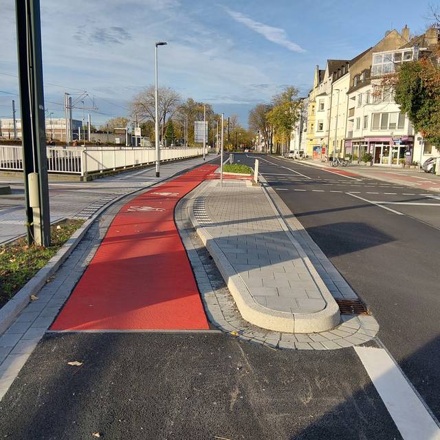 Neuer Radweg auf der Hildener Straße in Benrath. Er ist teilweise rot markiert. Links davon ist die Straßenbahntrasse zu erahnen, rechts sehen wir die Fahrbahn für Autos.