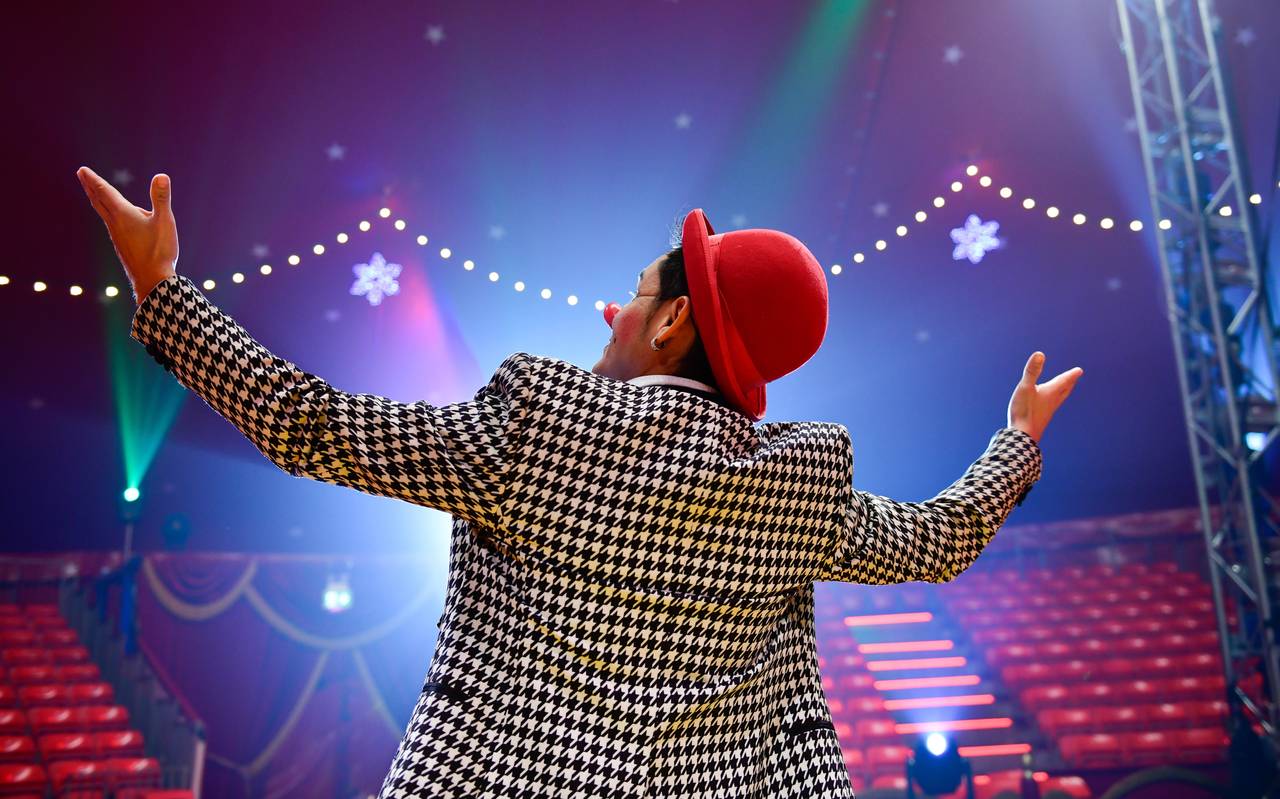 Ein Clown steht in der Manege und breitet die Arme aus, man sieht ihn von hinten