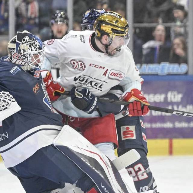 Ein Spieler der Düsseldorfer EG wird von einem Gegenspieler und dem gegnerischen Torwart in die Zange genommen.