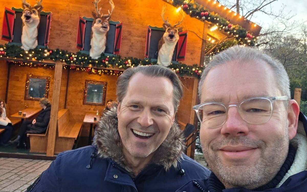 Antenne-Düsseldorf-Reporter Marc Pesch und Spitzenkoch Ernst Petry vor einer Bude auf dem Weihnachtsmarkt am Kö-Bogen.