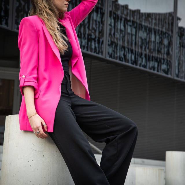 Eine junge Frau trägt einen Neon Pink Blaser