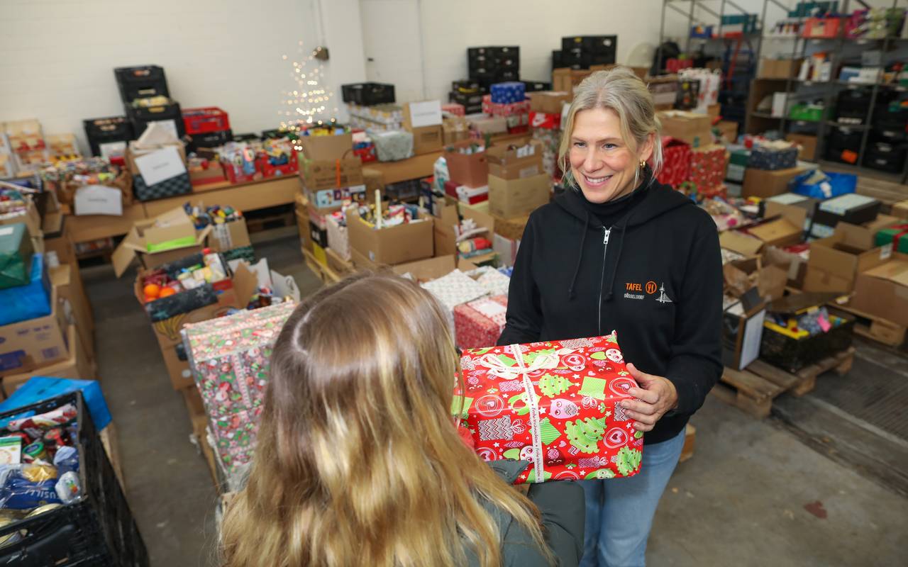 Eine Frau übergibt ein Weihnachtspaket an eine Frau der Tafel Düsseldorf. Die Tafel sammelt Päckchen für von Armut betroffenen Düsseldorfern.
