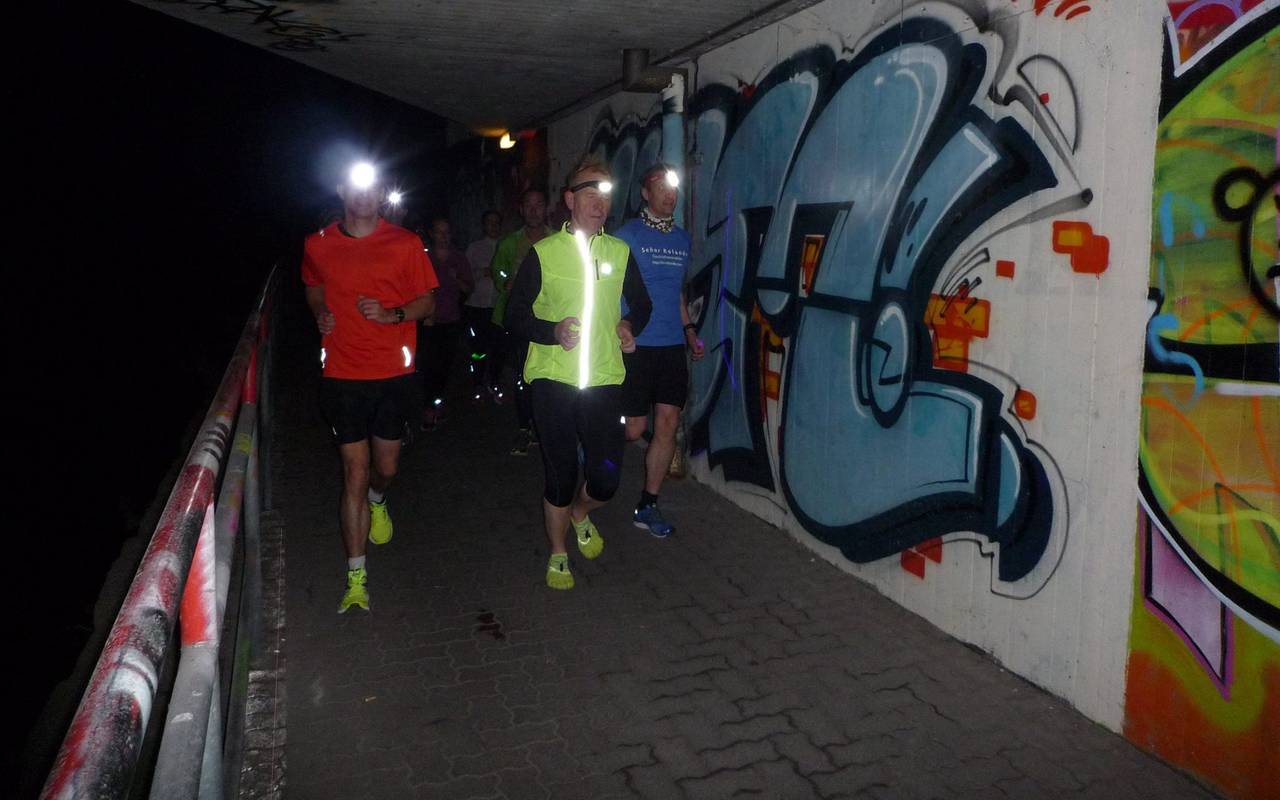 Läufer laufen nachts mit Stirnlampe durch Düsseldorf.