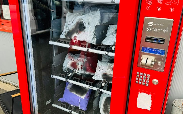 Ein roter Secret-Pack-Automat. Er ist mit Paketen gefüllt.