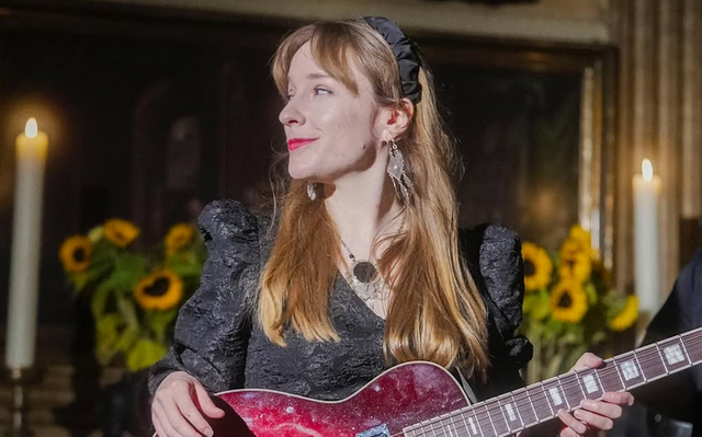 Lùisa aus Hamburg im schwarzen Dress mit roter E-Gitarre