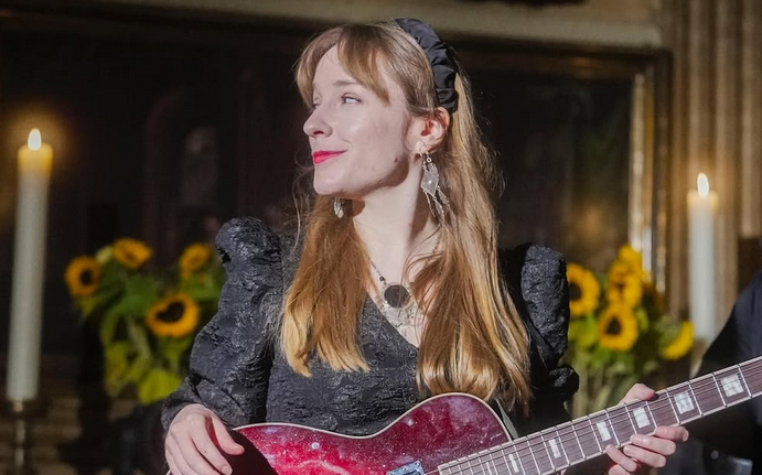 Lùisa aus Hamburg im schwarzen Dress mit roter E-Gitarre