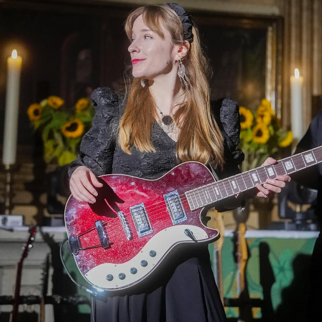 Lùisa aus Hamburg im schwarzen Dress mit roter E-Gitarre