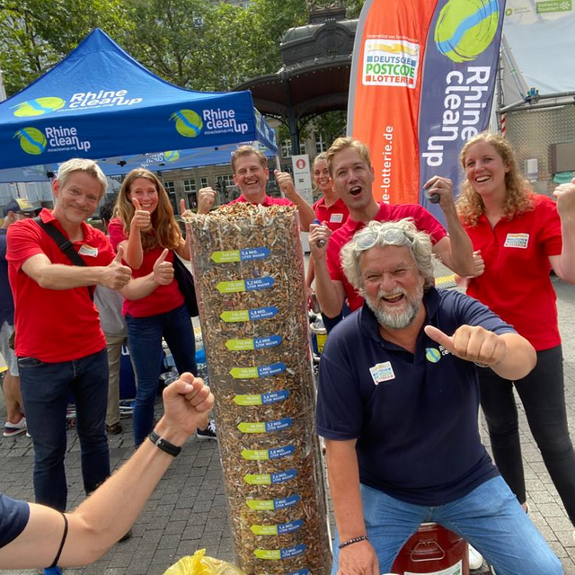 Das Team der Deutschen Postcode Lotterie vor einer Säule mit gesammelten Kippen in der Kippen-Woche.