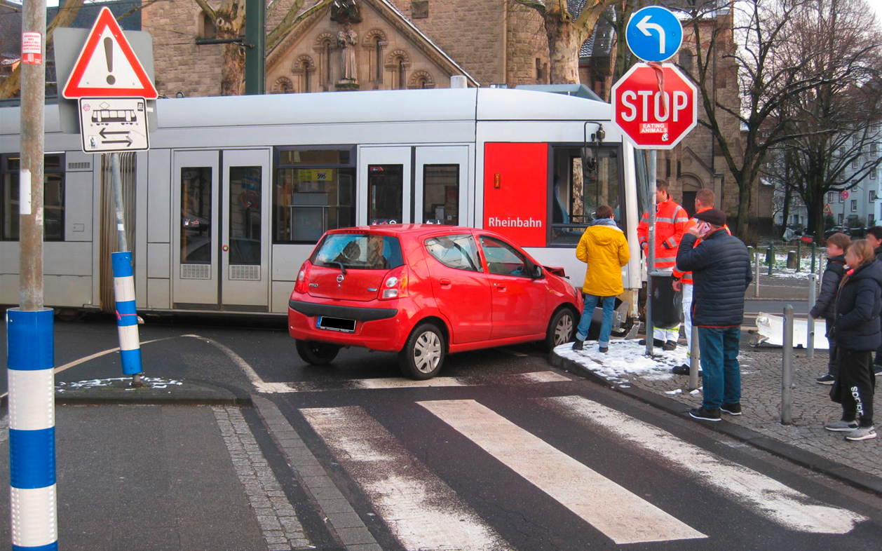 Ein rotes Auto und eine Straßenbahn sind auf einer Kreuzung ineinander gefahren.