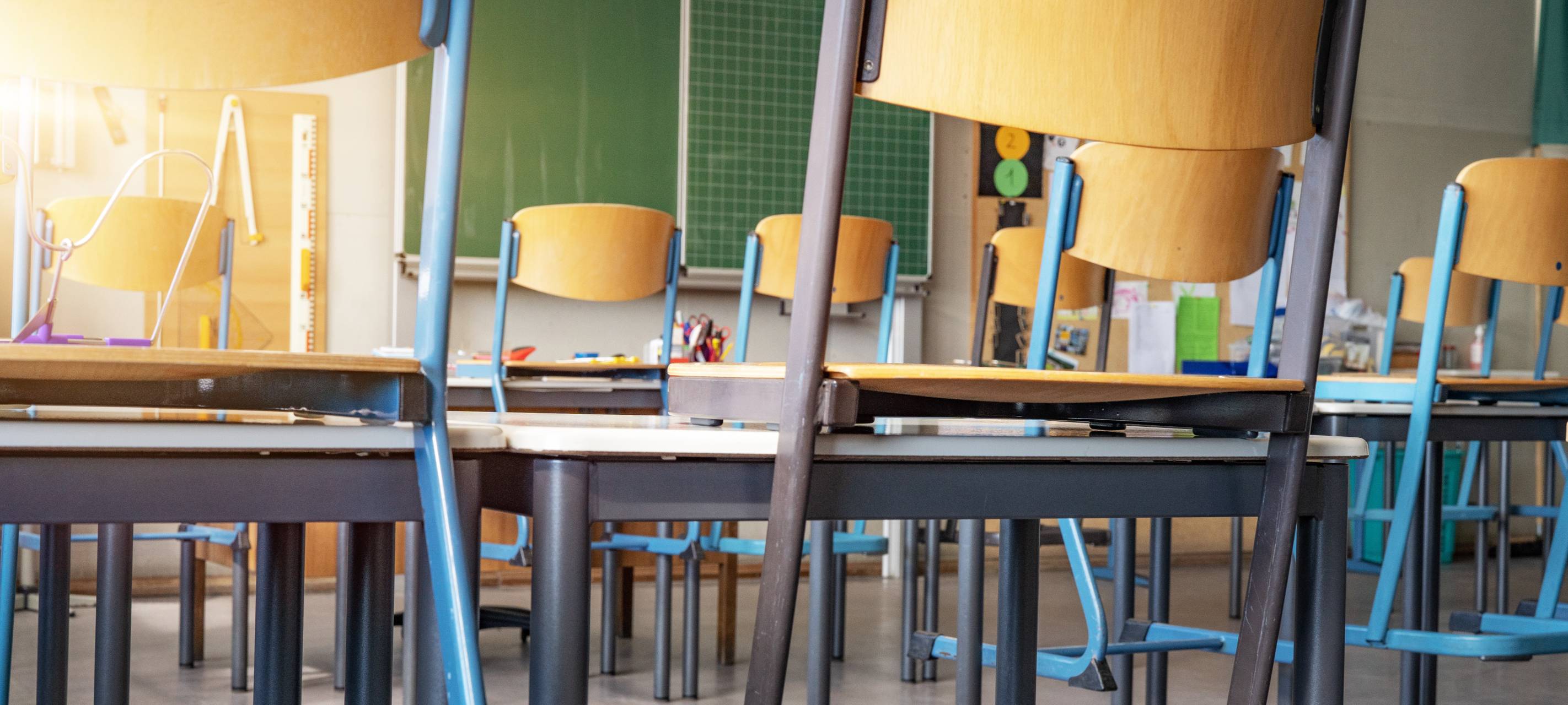 Leeres Klassenzimmer mit Stühlen auf den Tischen und leerer Tafel.