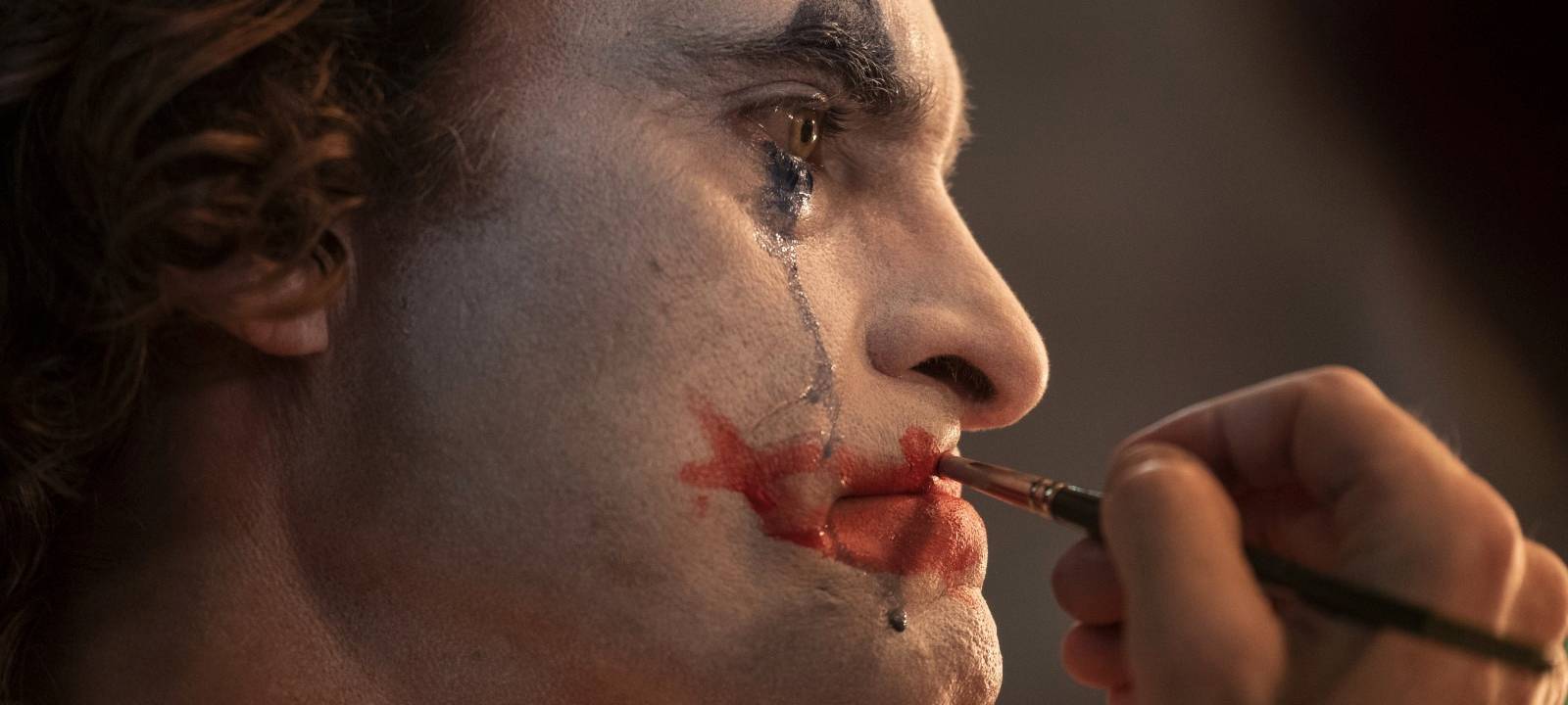 Arthur schminkt sich als Clown Joker.