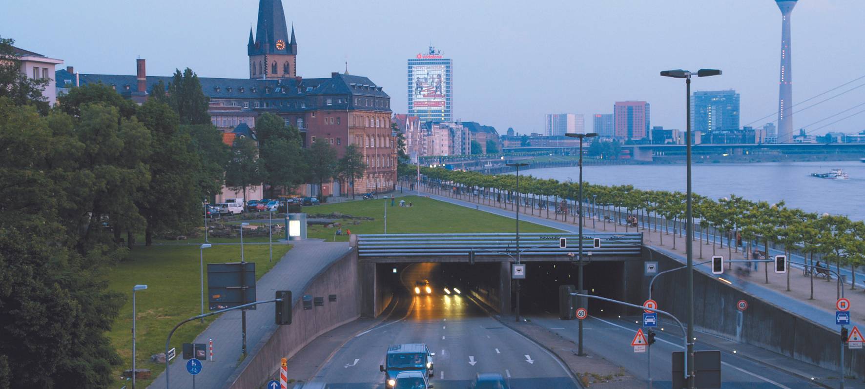 Der Rheinufertunnel am Nordausgang, bzw. Nordeingang. Im Hintergrund die Skyline von Düsseldorf mit dem Rheinturm und St. Lambertus.