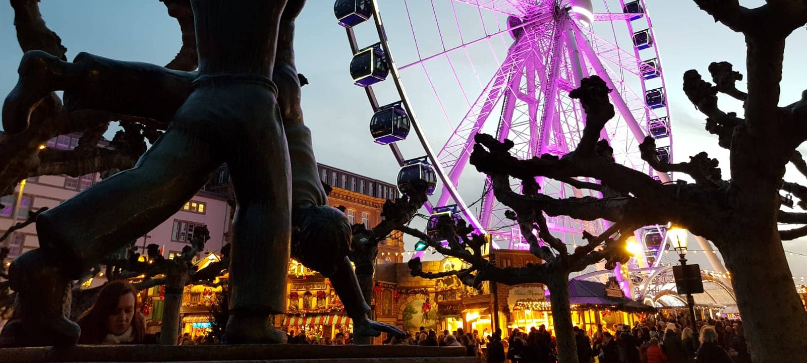 Ein Bild vom Radschlägerbrunnen auf dem Burgplatz. Im Hintergrund das Riesenrad "Wheel of Vision".