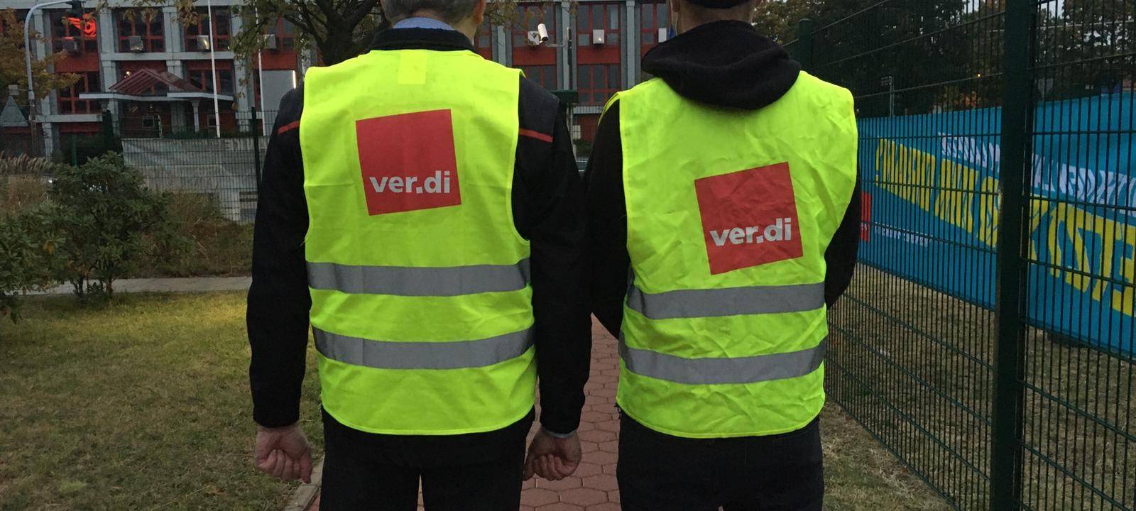 Zwei Männer in gelber Streikweste, auf dem Rücken steht Verdi