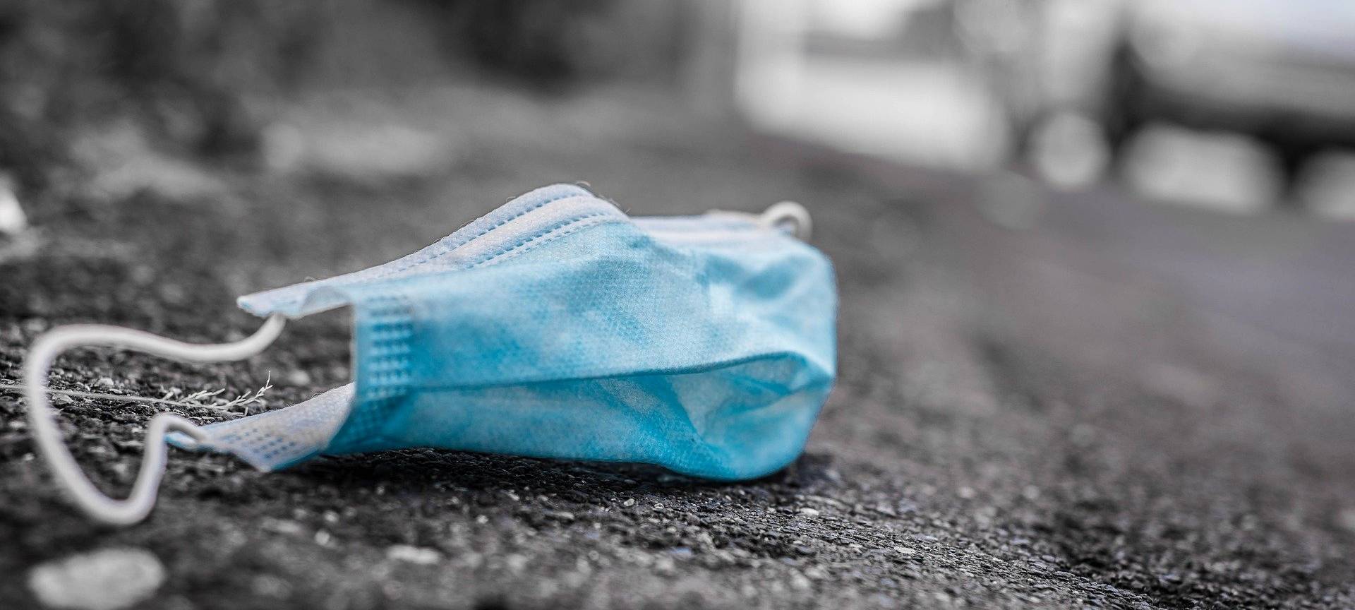 Eine gebrauchte und weggeworfene Corona-Maske auf dem Bürgersteig.