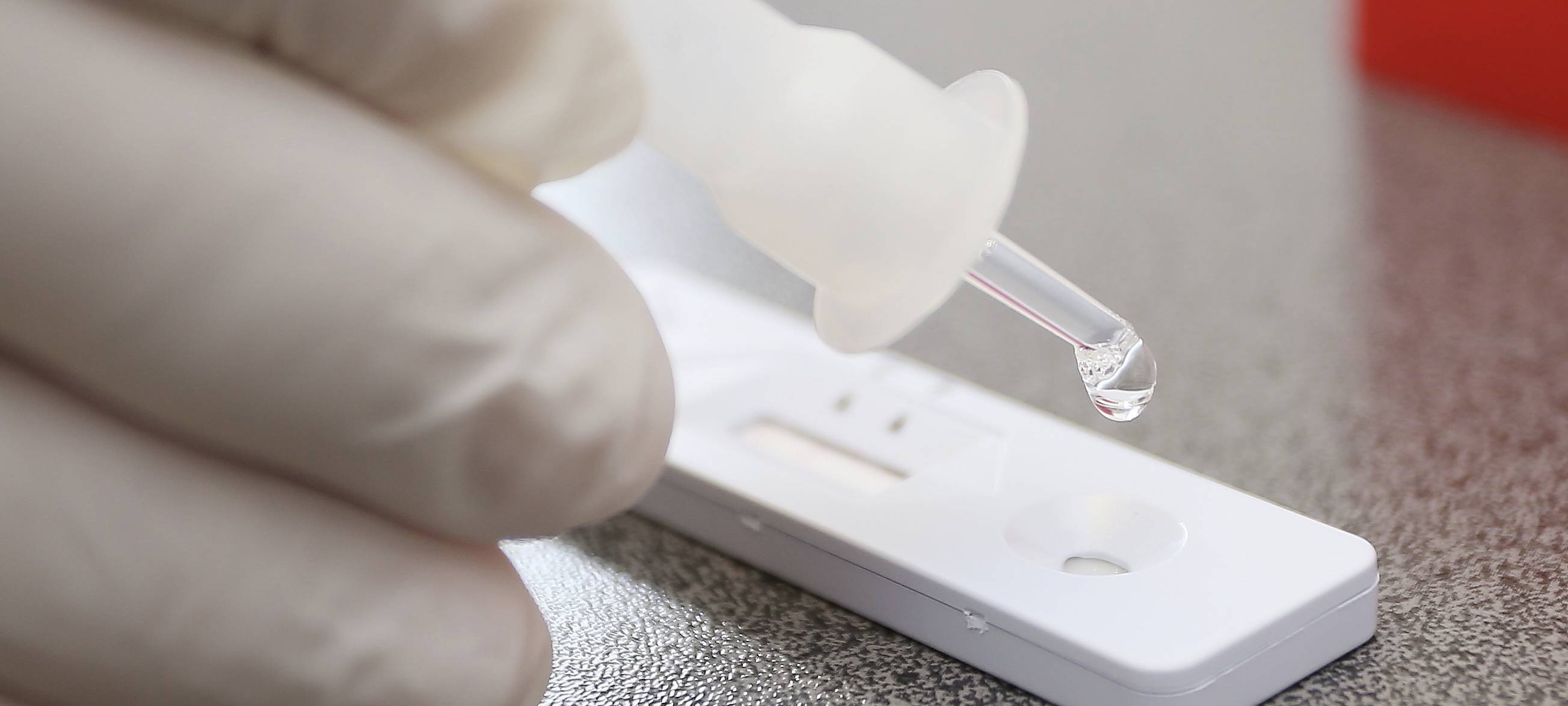 Eine Person benutzt einen Covid19-Test. Zu sehen ist ein Tropfer der Testflüssigkeit.