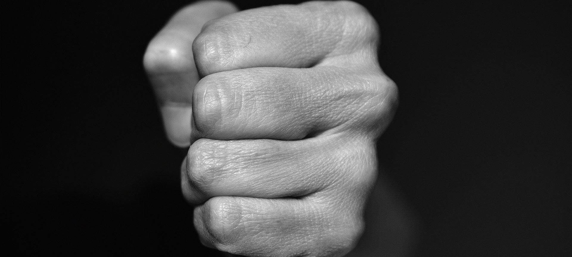 Eine zur Faust geballte Hand vor schwarzem Hintergrund.