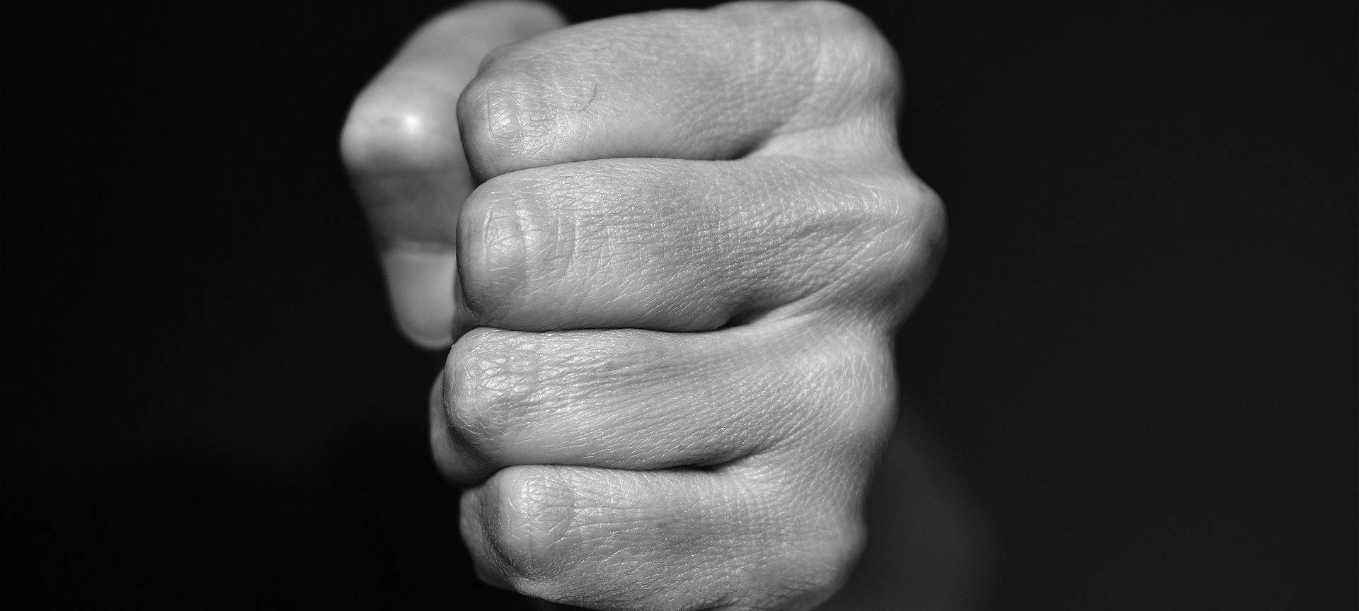 Eine zur Faust geballte Hand vor schwarzem Hintergrund.