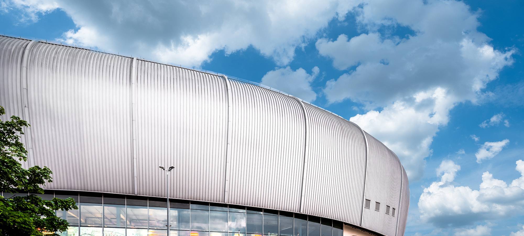 Der Rather Dome mit dem DEG-Logo im Vordergrund. Im Hintergrund ist blauer Himmel mit einigen Wolken.