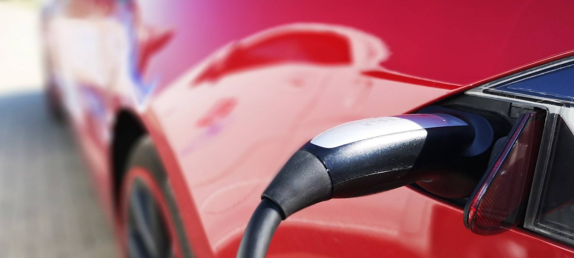 Ein rotes Elektroauto hängt am Strom und wird gerade geladen.