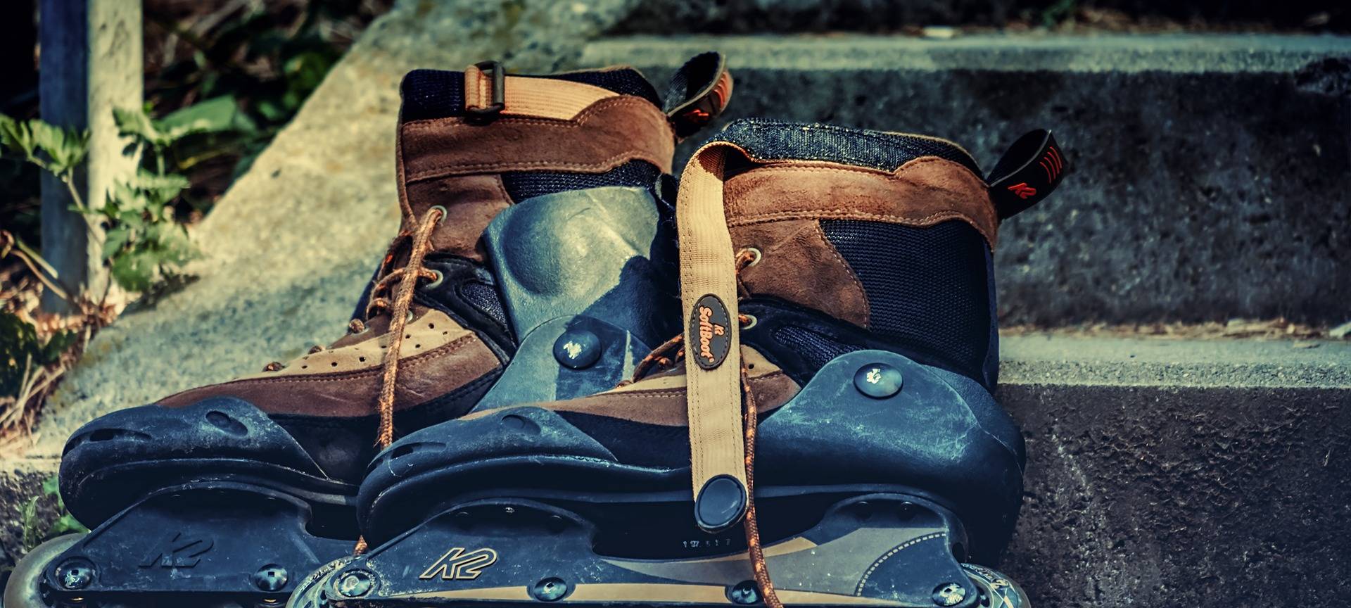 Schwarz-braune Rollerblades liegen auf einem Stein. Manche nennen sie auch Inlineskates.