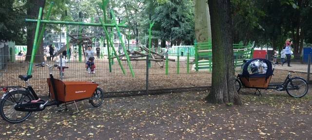 Lastenräder stehen vor einem Spielplatz.