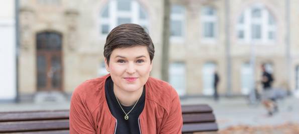 Sara Nanni vom Bündnis 90/ Die Grünen sitzt auf einer Bank und blickt in die Kamera.