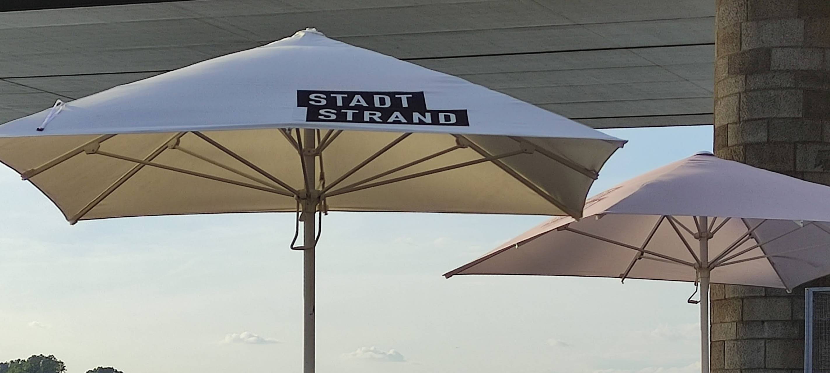 Ein geöffneter Sonnenschirm am Düsseldorfer Stadtstrand am Rhein.