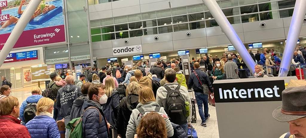 Menschen stehen am Flughafen Düsseldorf in einer langen Warteschlange.