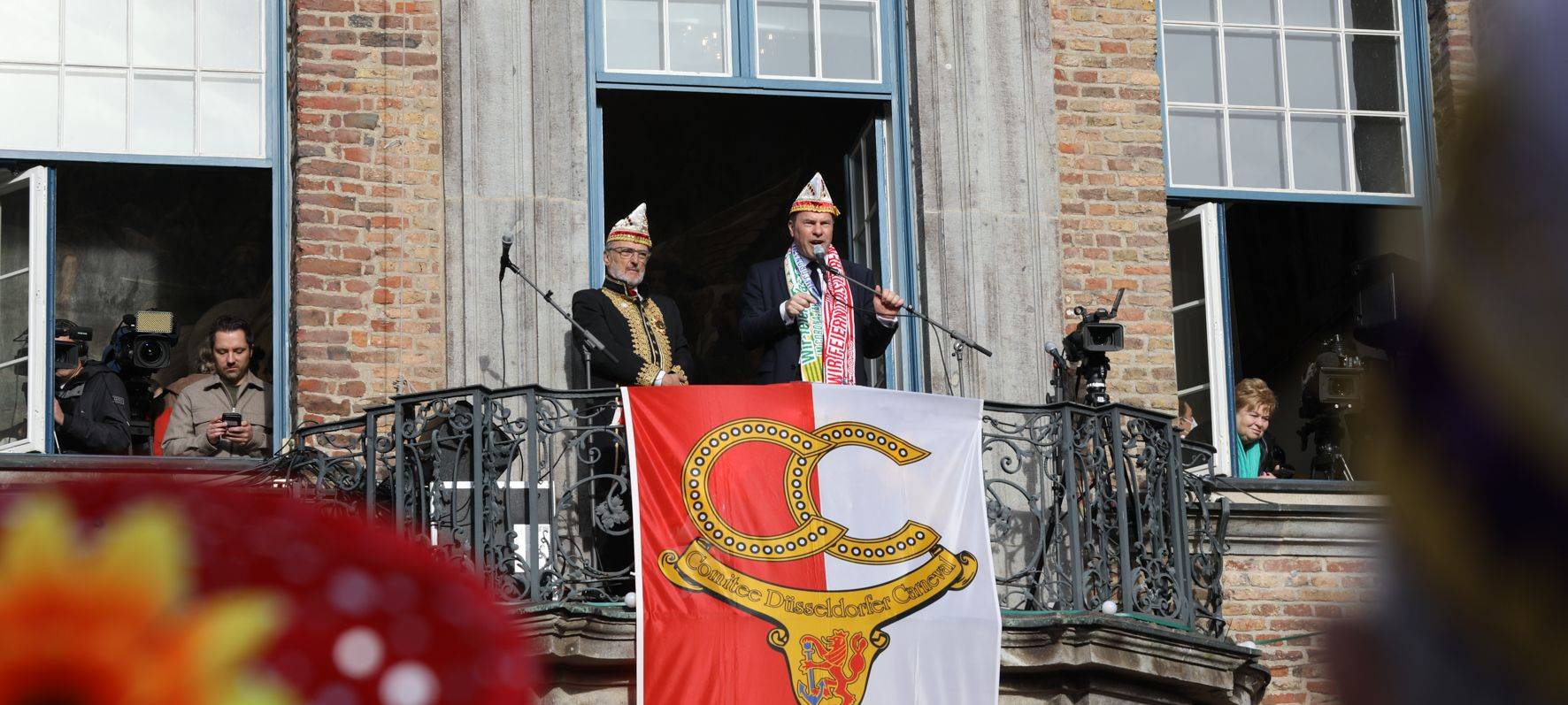 Oberbürgermeister Stephan Keller auf dem Rathaus-Balkon. Er trägt eine Narrenkappe.