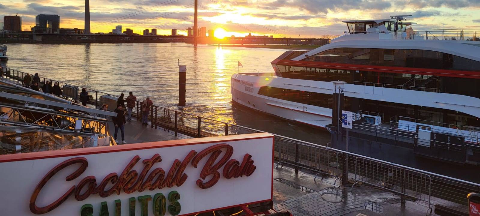 Die Rheinuferpromenade mit Sonnenuntergang und Rheinturm.