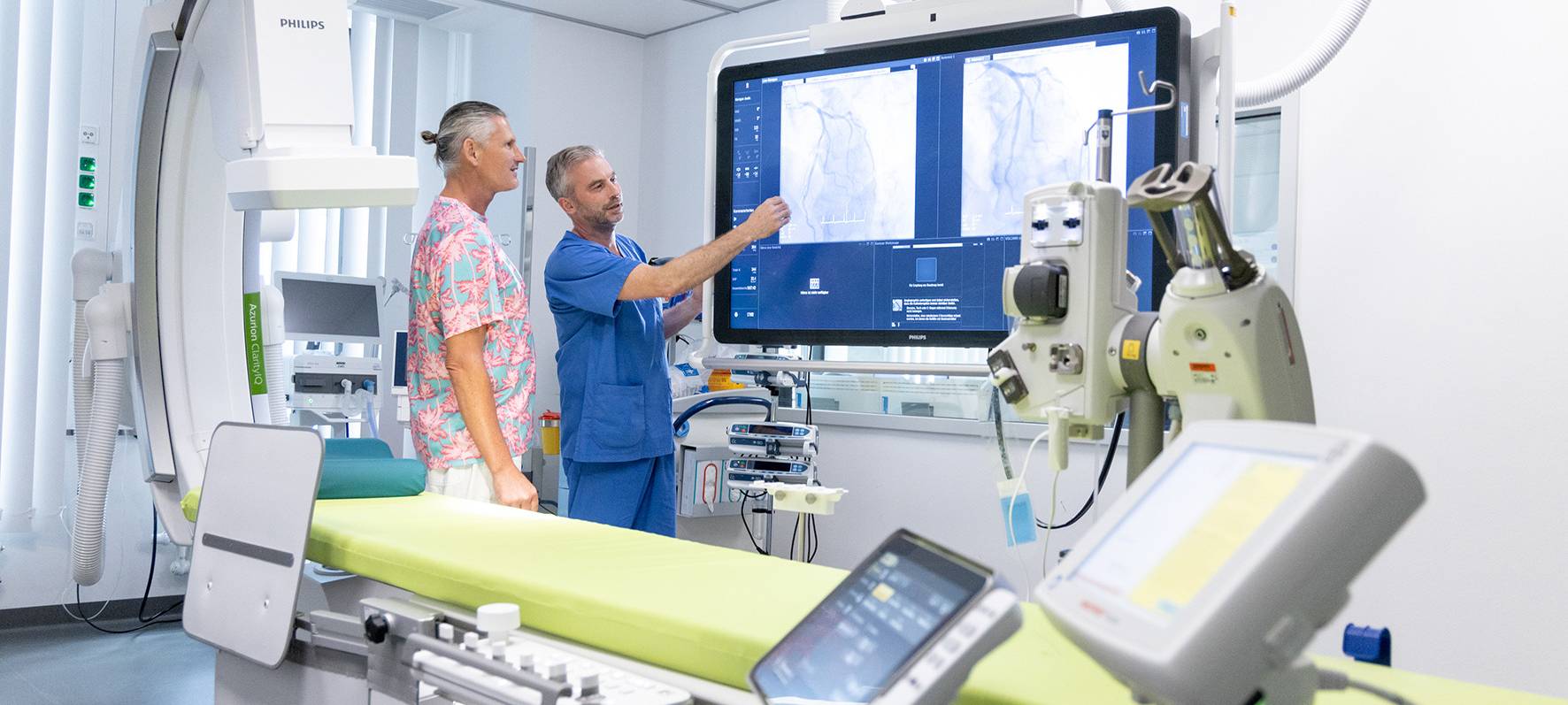 Zum Aufbau des Atemnotfallzentrums ist am Florence-Nightingale Krankenhaus 2022 ein hochmodernes Herzkatheterlabor in Betrieb gegangen. Dr. med. Dierk Rulands, Departmentleiter Kardiologie, erklärt einem Patienten, wie sein Herzinfarkt behandelt wurde.