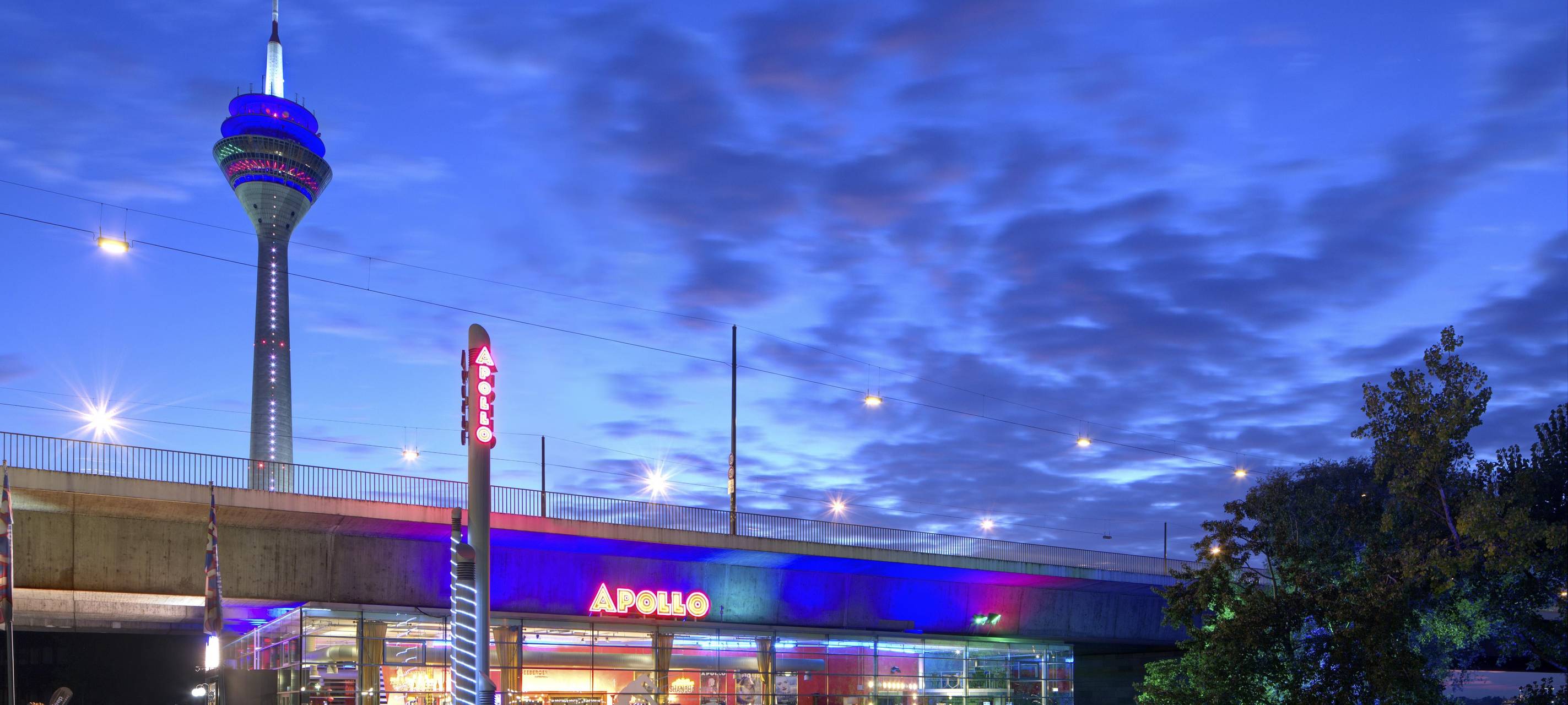 Das Apollo-Varieté unter der Rheinkniebrücke. Im Hintergrund leuchtet der Rheinturm.