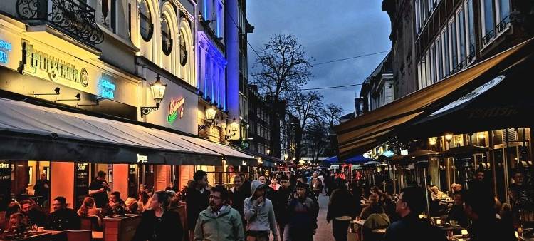 Menschen gehen am Abend durch die Altstadt über die Bolker Straße.