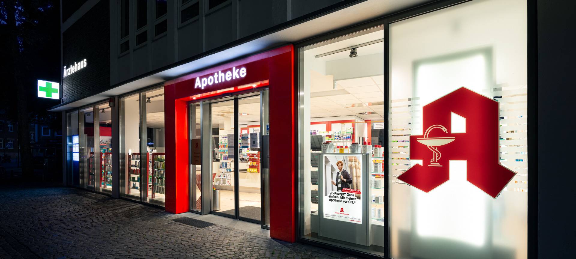 Die Frontansicht einer Apotheke. Es ist dunkel.