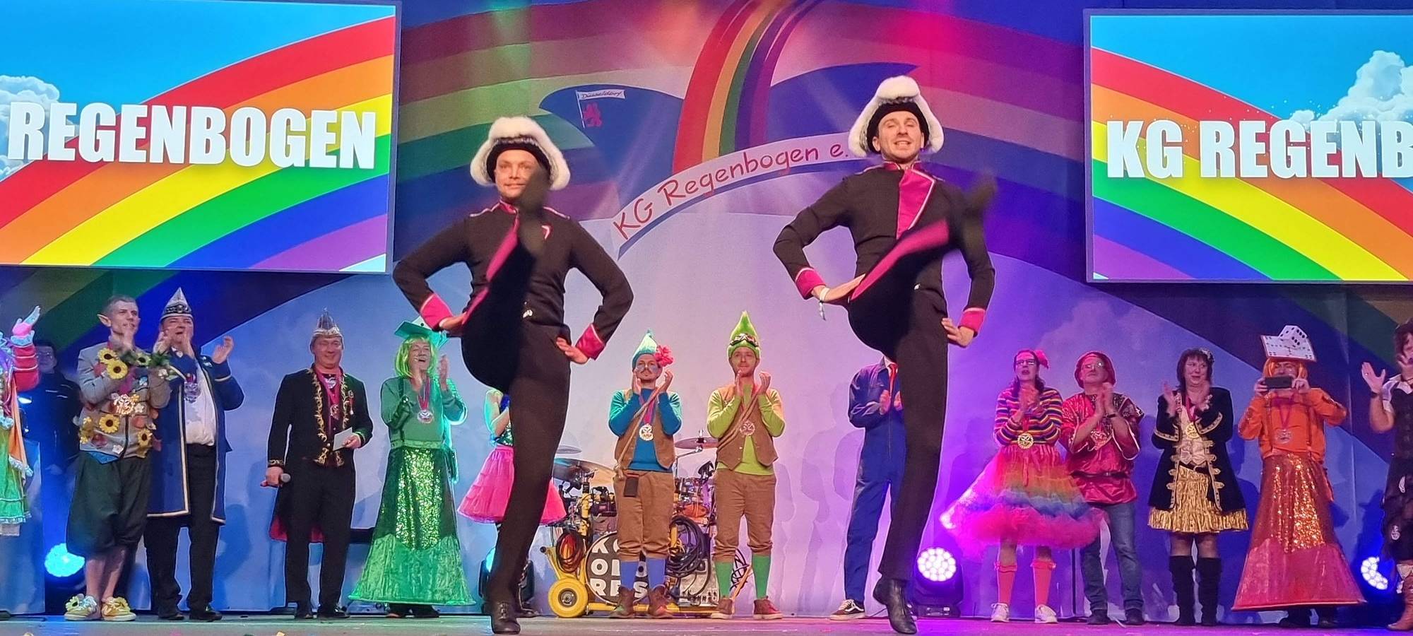 Das Tanzpaar der KG Regenbogen bei einem Auftritt. Beide Tänzer tanzen auf einer Bühne.