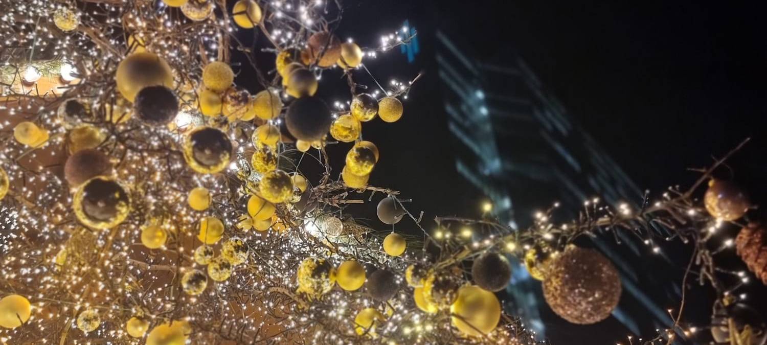 Gelber Weihnachtsschmuck und Lichter in einem Baum.
