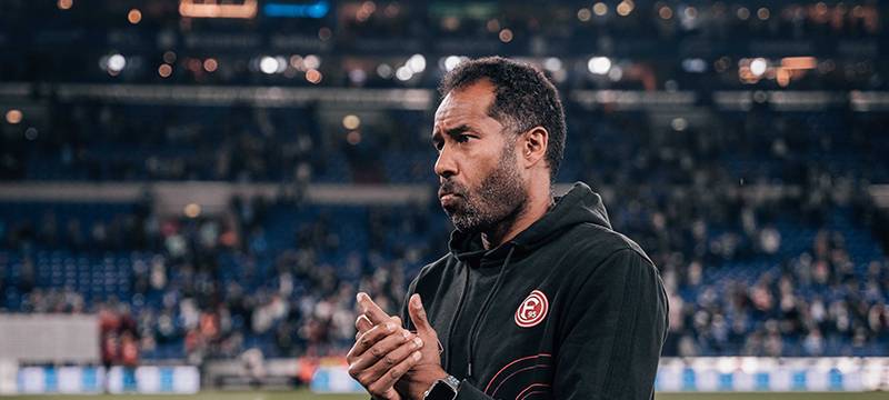 Daniel Thioune, der Fortuna-Trainer, steht auf dem Spielfeld und reibt sich die Hände.