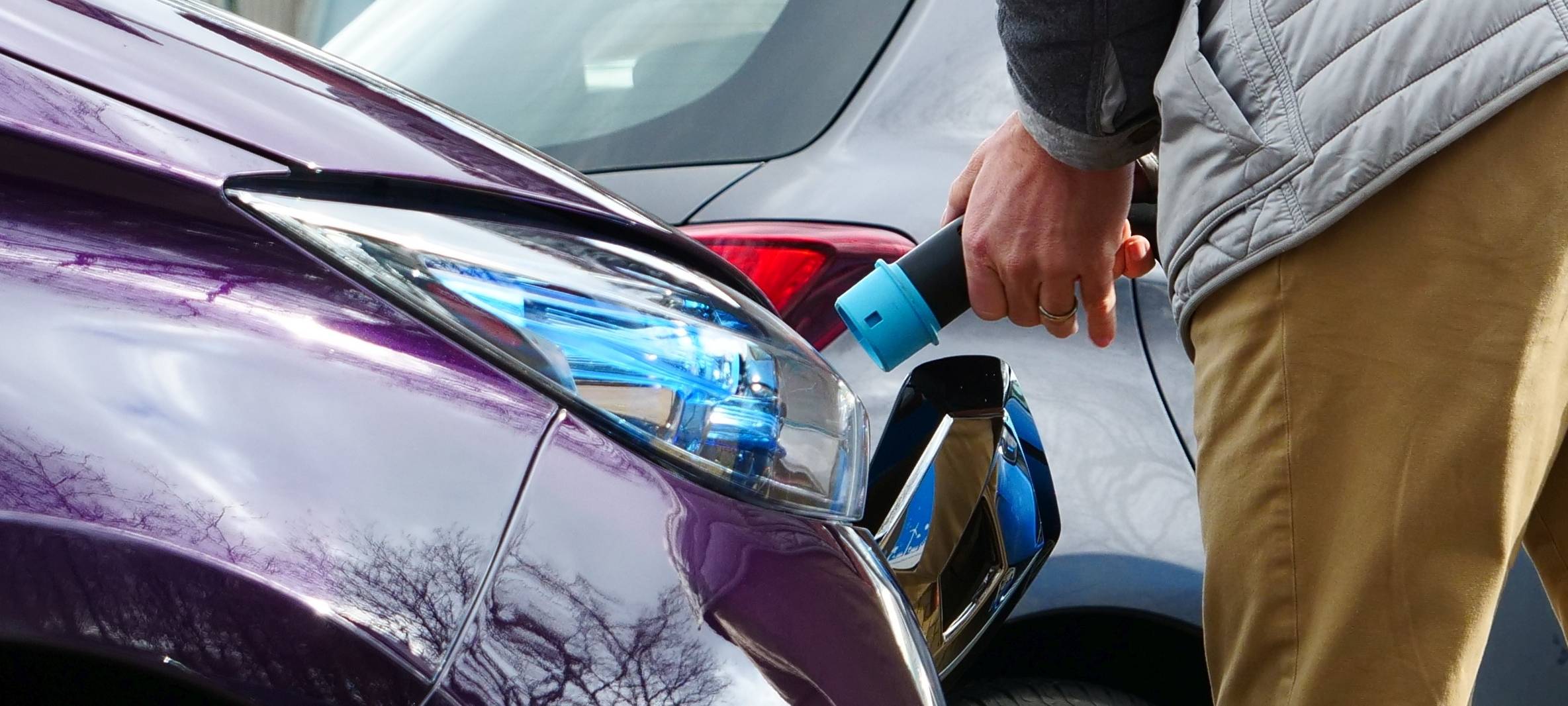 Ein Mann startet den Ladevorgang an einem Elektroauto.