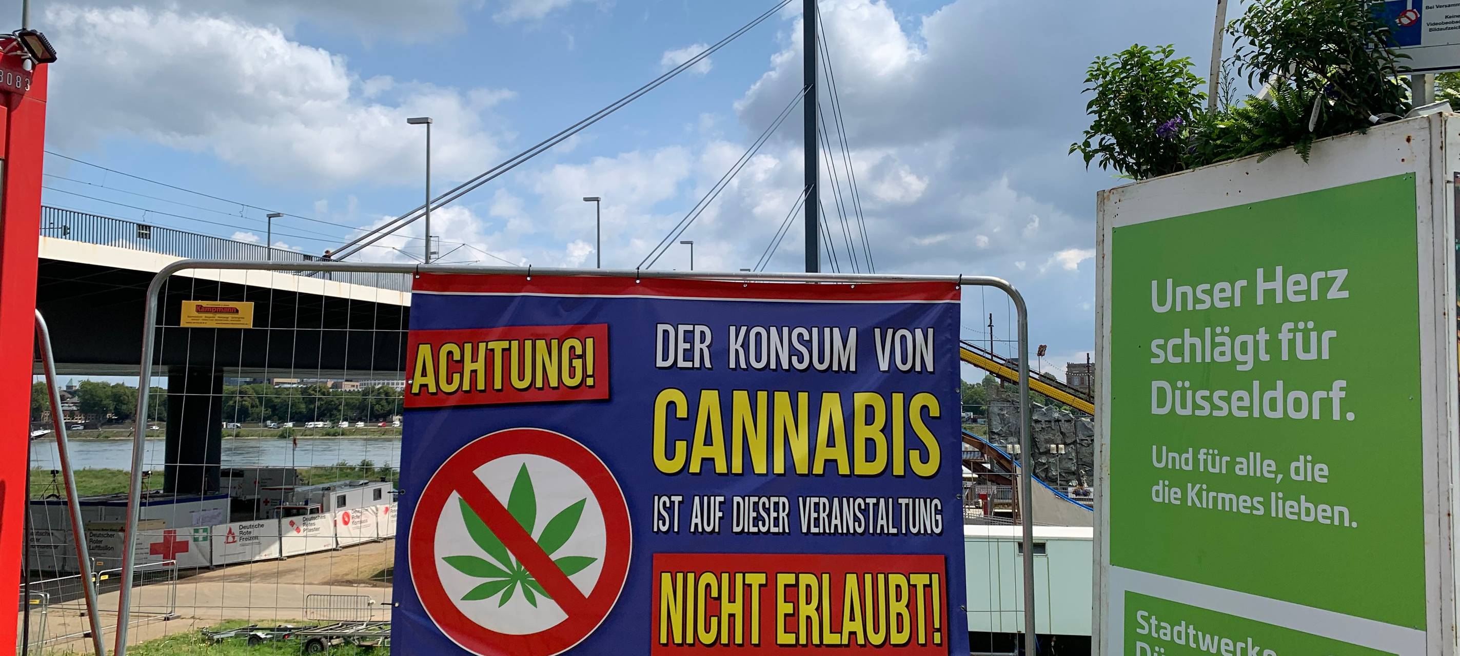 Cannabis-Verbot auf der Rheinkirmes. Darauf macht ein Schild auf den Rheinwiesen aufmerksam.