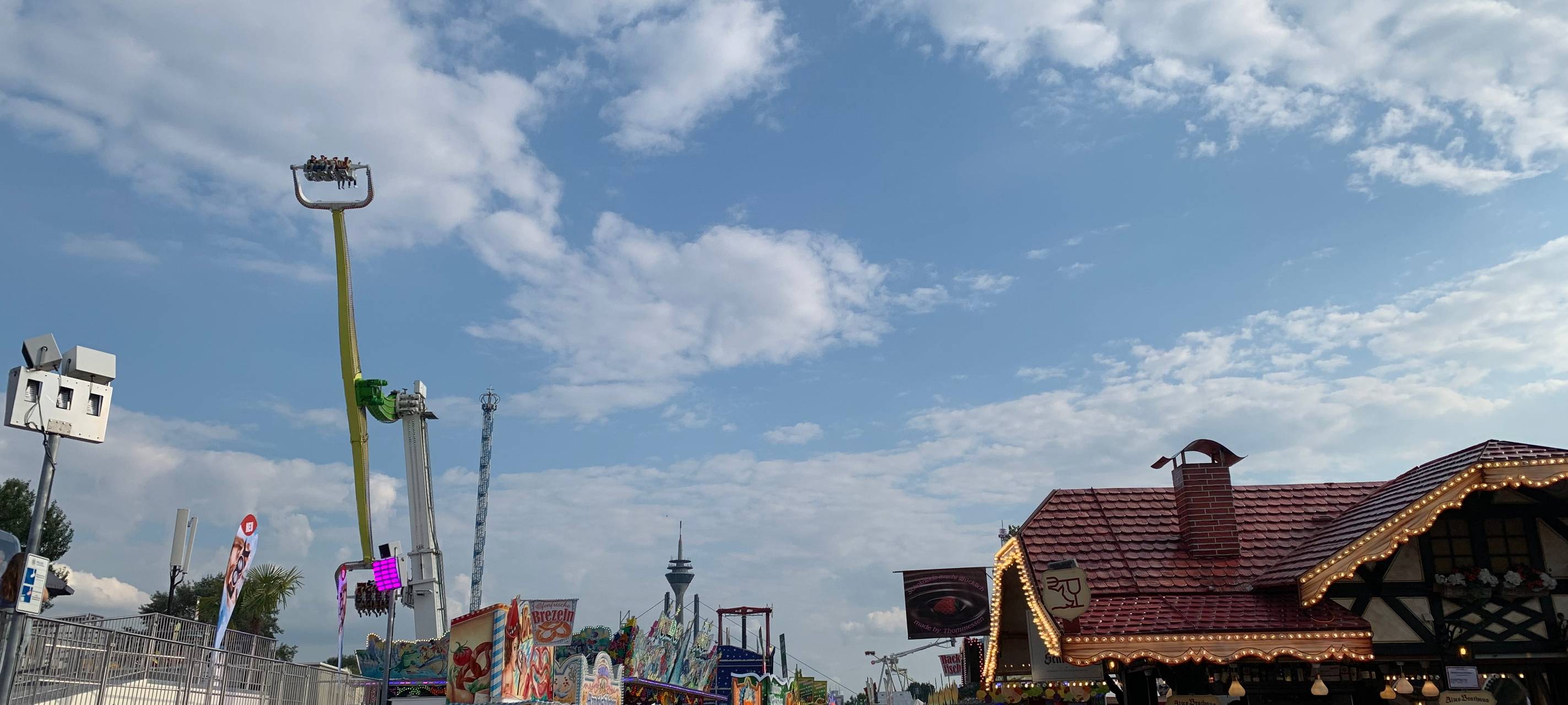 Die Rheinkirmes bei schönem Wetter. Viele Menschen schlendern über den Platz und an den Fahrgeschäften vorbei.