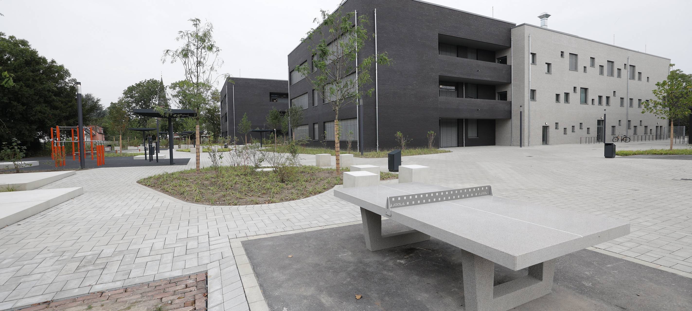 Der Neubau der Realschule an der Borbecker Straße in Rath. Im Vordergrund ist eine Tischtennisplatte. Hintergrund das Schulgebäude.