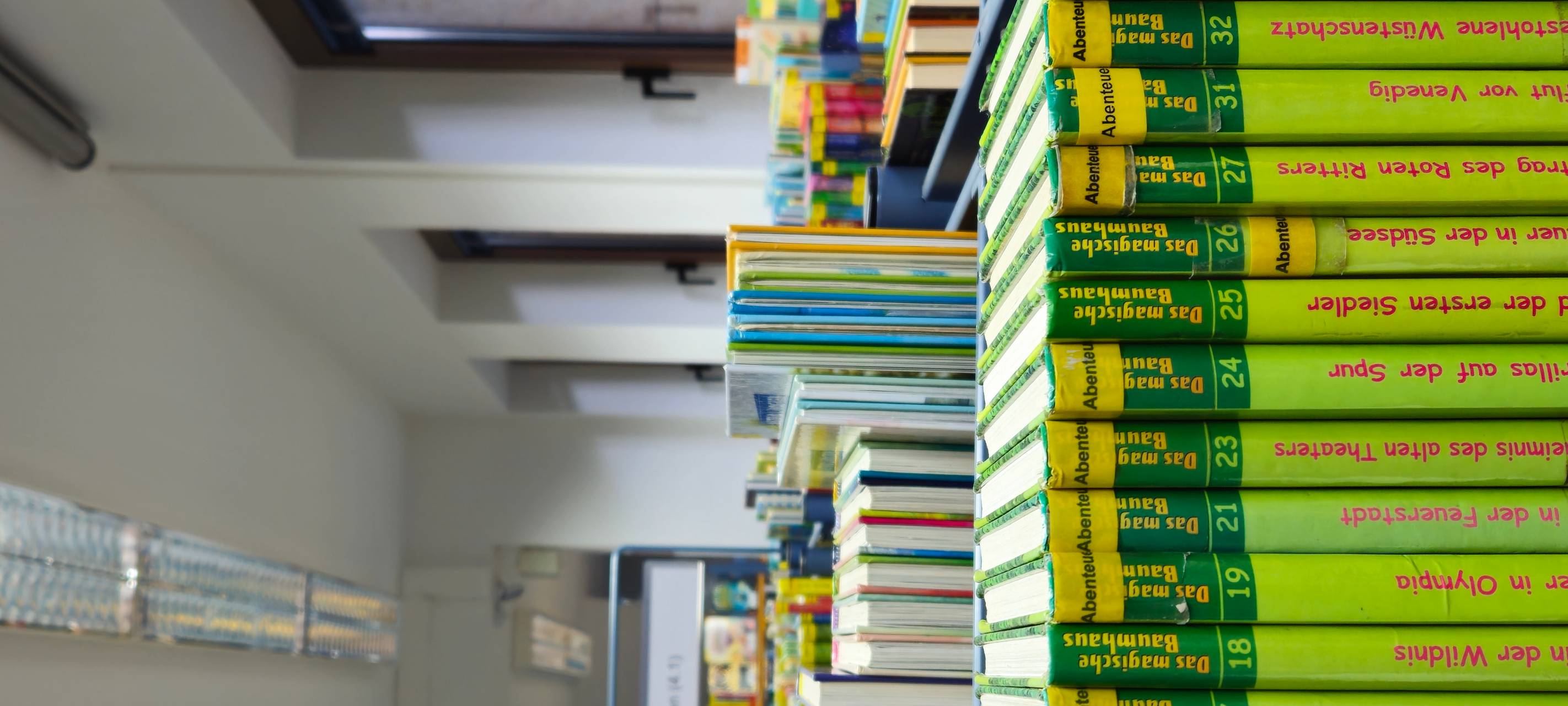 Blick in eine Bücherei, rechts stehen grüne Bücher