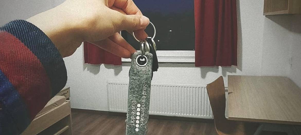 Eine Frau hält einen Schlüssel in einem Studentenzimmer.