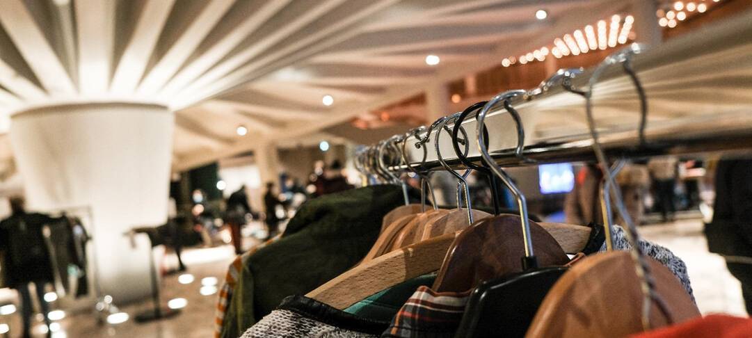 Kleidungsstücke hängen auf einem Ständer. Sie sind Teil einer Kleidertauschparty.