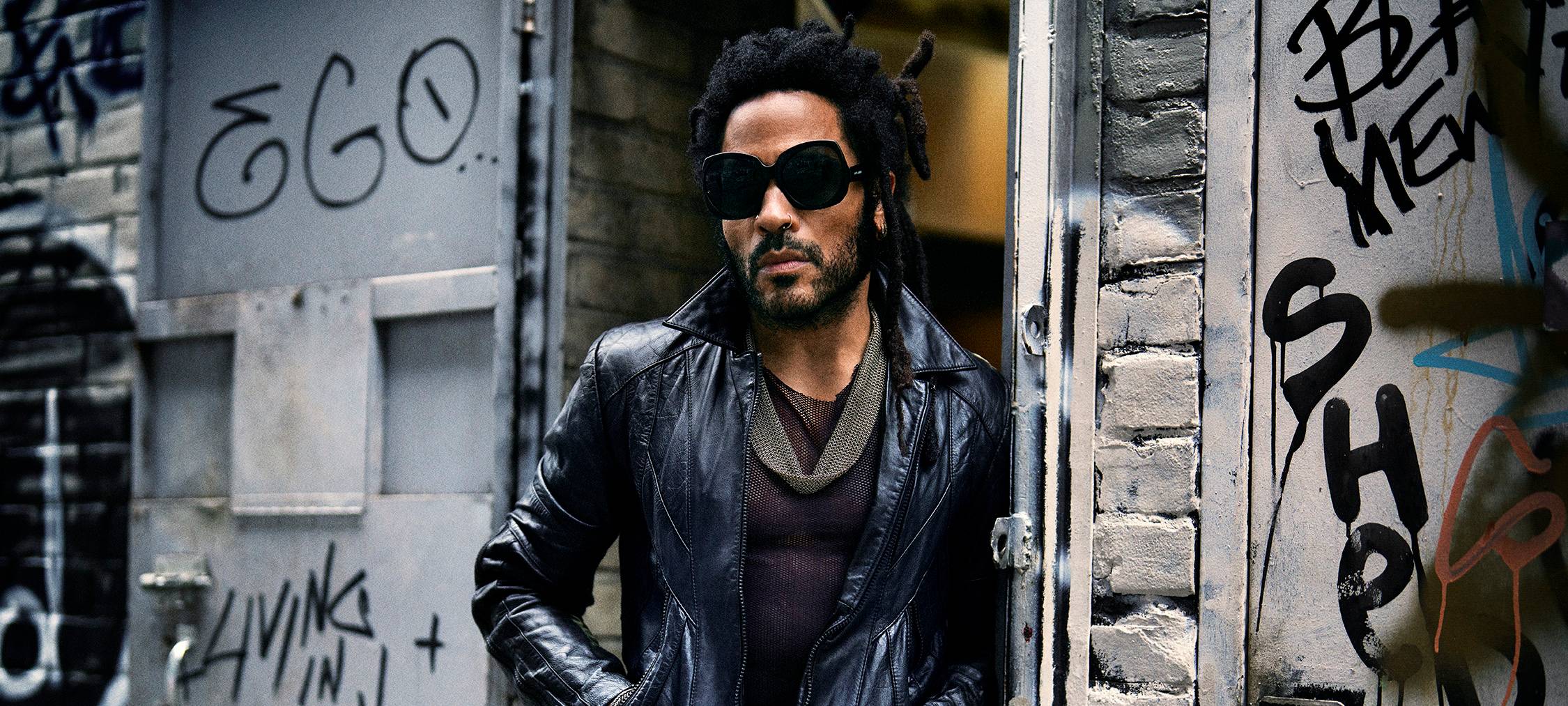 Der Sänger Lenny Kravitz posiert mit Lederjacke und Sonnenbrille.